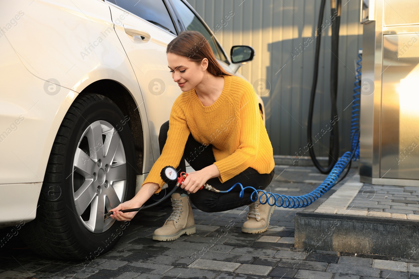 Photo of Young woman inflating tire at car service