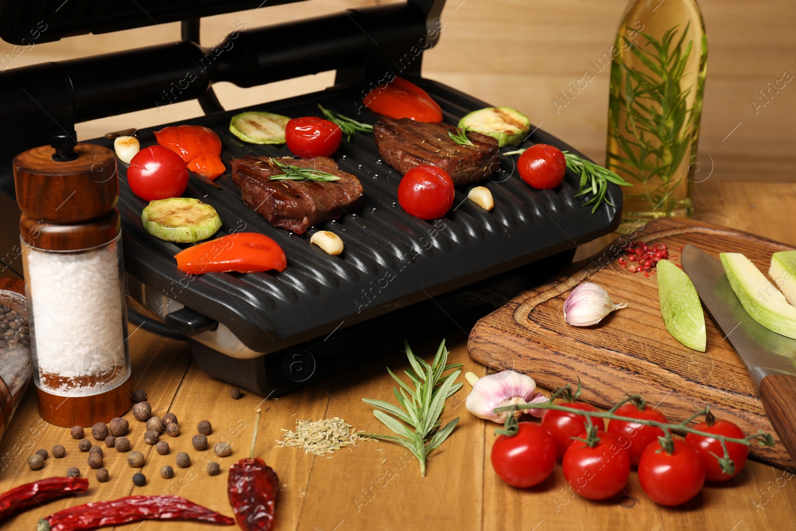 Photo of Electric grill with different products on wooden table