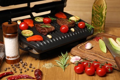 Photo of Electric grill with different products on wooden table