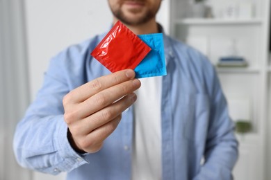 Closeup of man showing packs with condoms indoors
