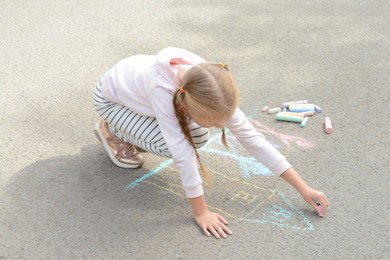 Photo of Little child drawing happy family with chalk on asphalt