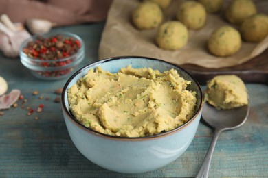 Photo of Bowl of chickpea puree on blue wooden table. Falafel recipe