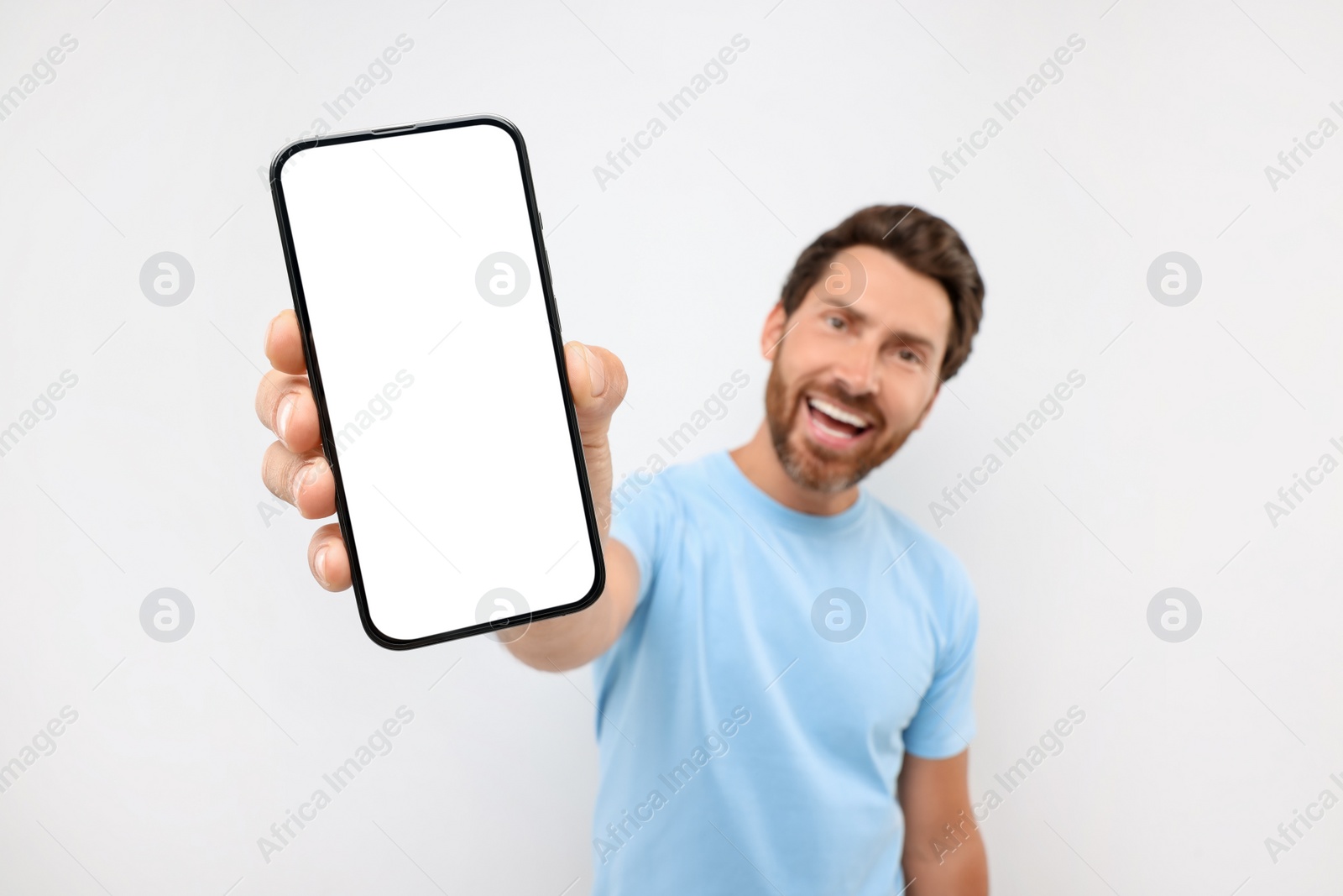 Photo of Handsome man showing smartphone in hand on white background, selective focus. Mockup for design