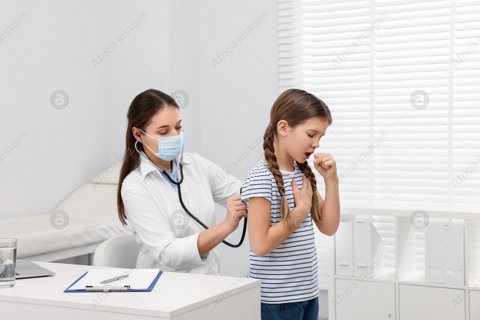 Photo of Doctor examining coughing girl in hospital. Cold symptoms