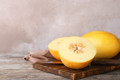 Photo of Sliced ripe melon on wooden table against color background. Space for text