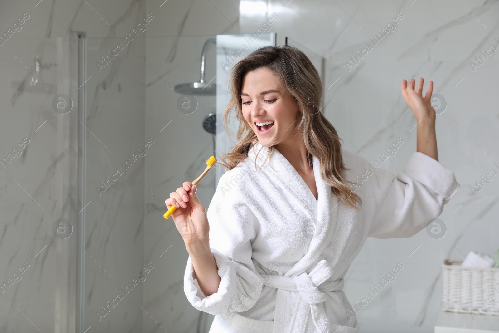 Photo of Beautiful young woman singing into toothbrush in bathroom