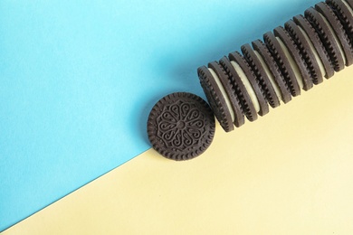 Tasty chocolate cookies with cream on color background, top view. Space for text