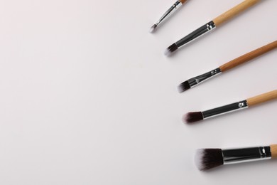 Photo of Set of makeup brushes on white background, flat lay. Space for text