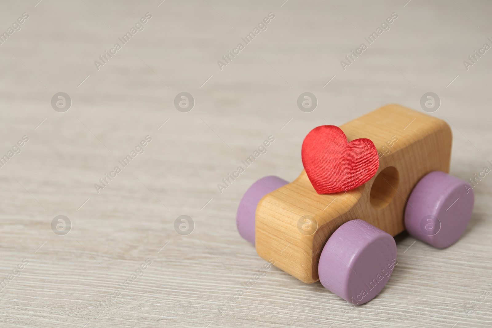 Photo of Wooden toy with and decorative heart on table, space for text. Happy Valentine's Day