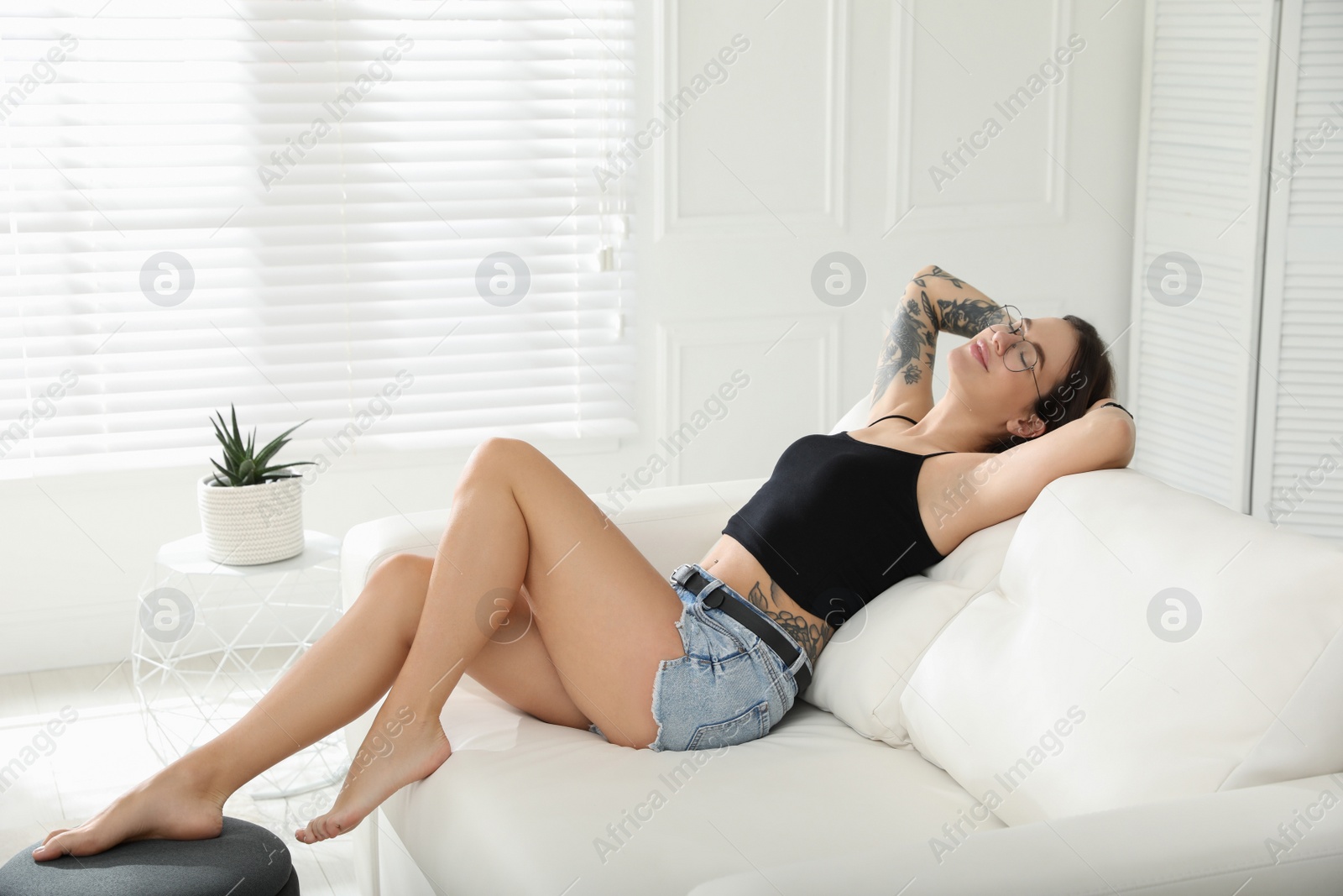 Photo of Beautiful woman with tattoos on body resting in living room