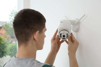 Technician installing CCTV camera on wall indoors