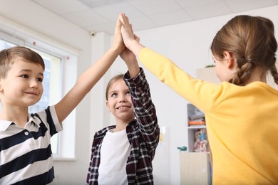 Photo of Happy children giving high five at school
