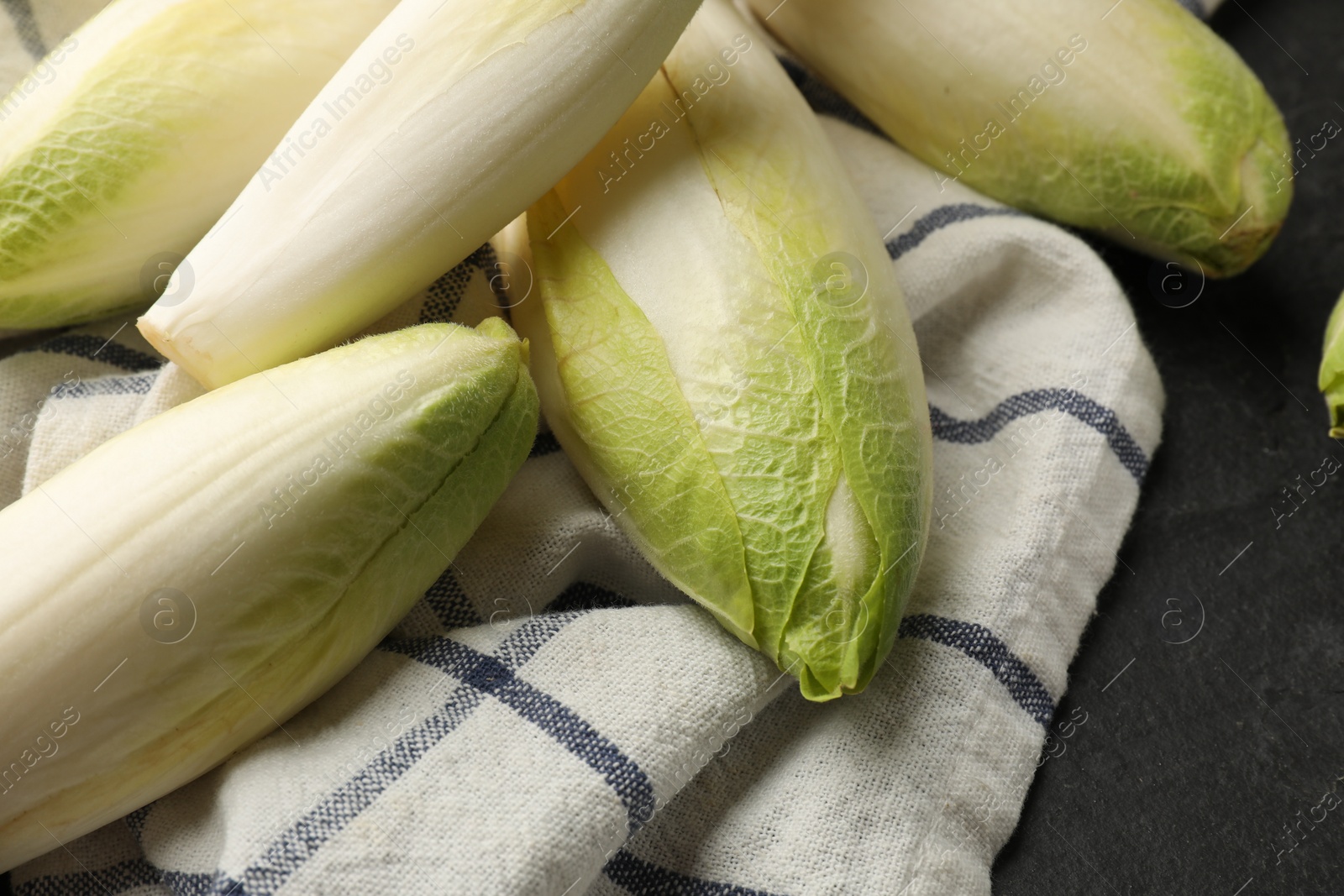 Photo of Fresh raw Belgian endives (chicory) on black table, closeup