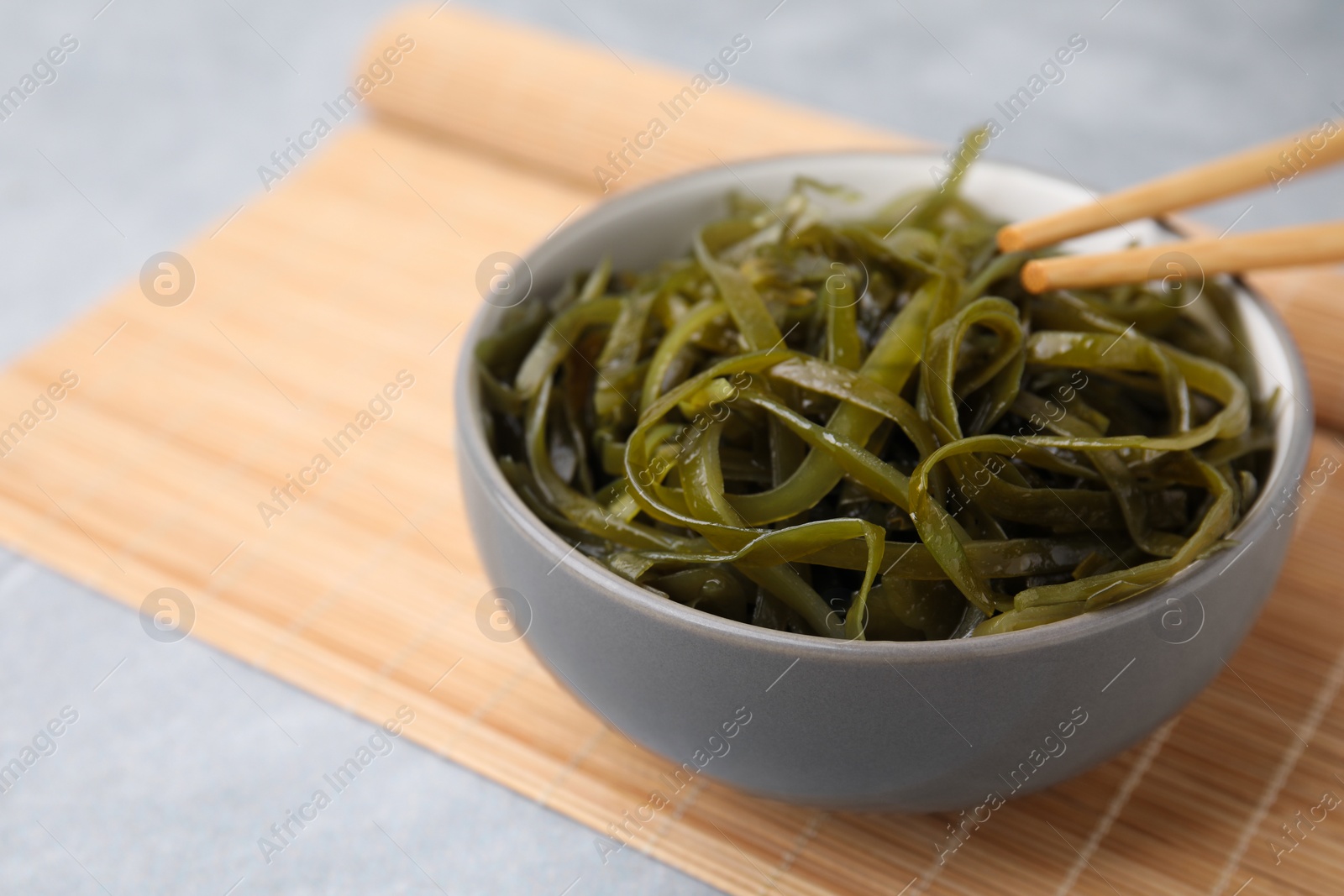 Photo of Tasty seaweed salad in bowl served on gray table, closeup