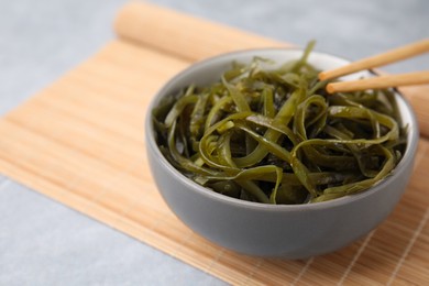 Photo of Tasty seaweed salad in bowl served on gray table, closeup