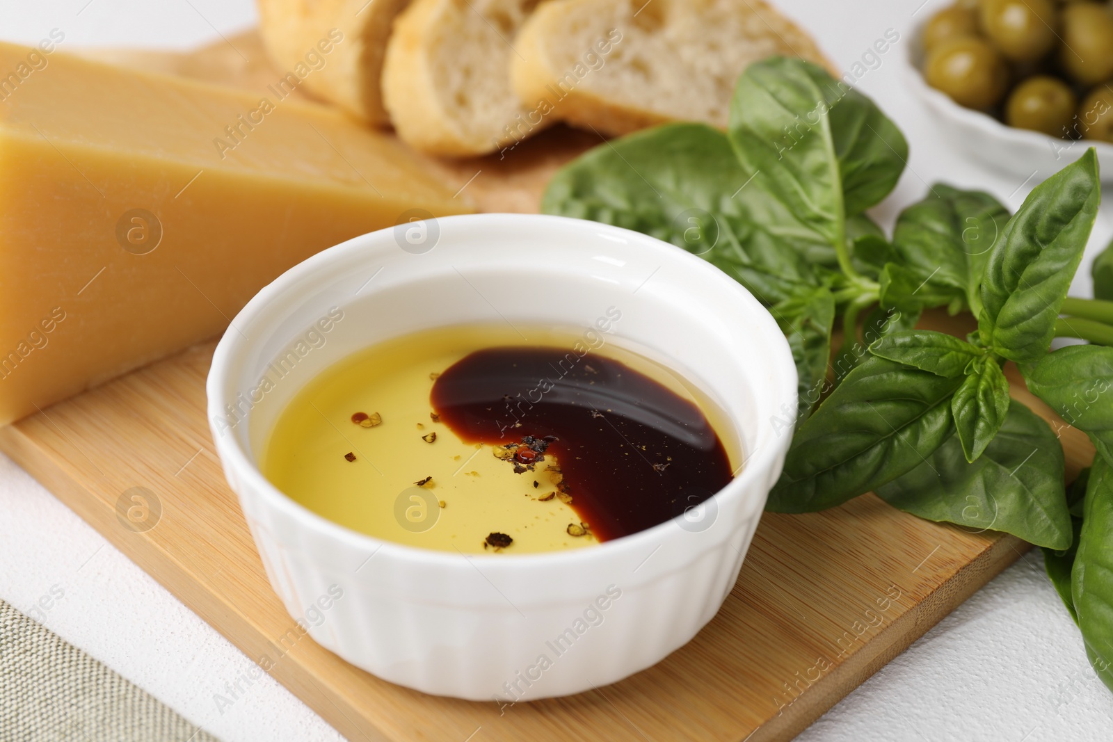 Photo of Bowl of organic balsamic vinegar with oil, basil and other products on table, closeup
