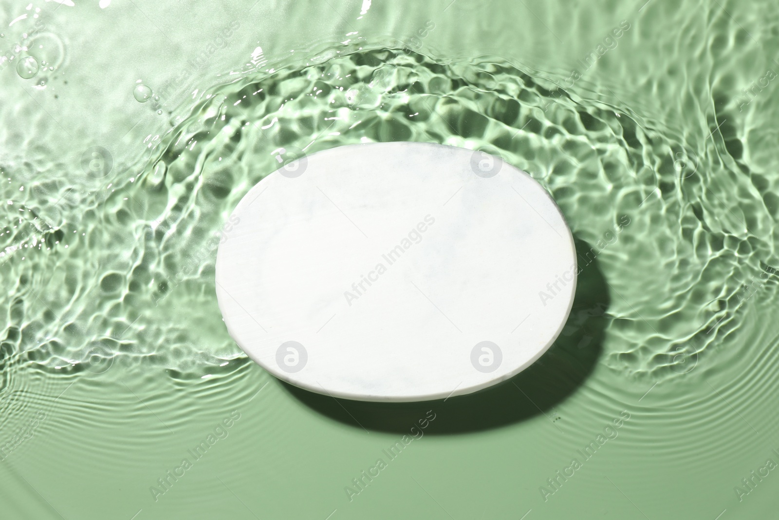 Photo of Presentation for product. Marble podium in water on green background, top view