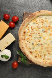 Delicious cheese pizza and ingredients on dark grey table, flat lay