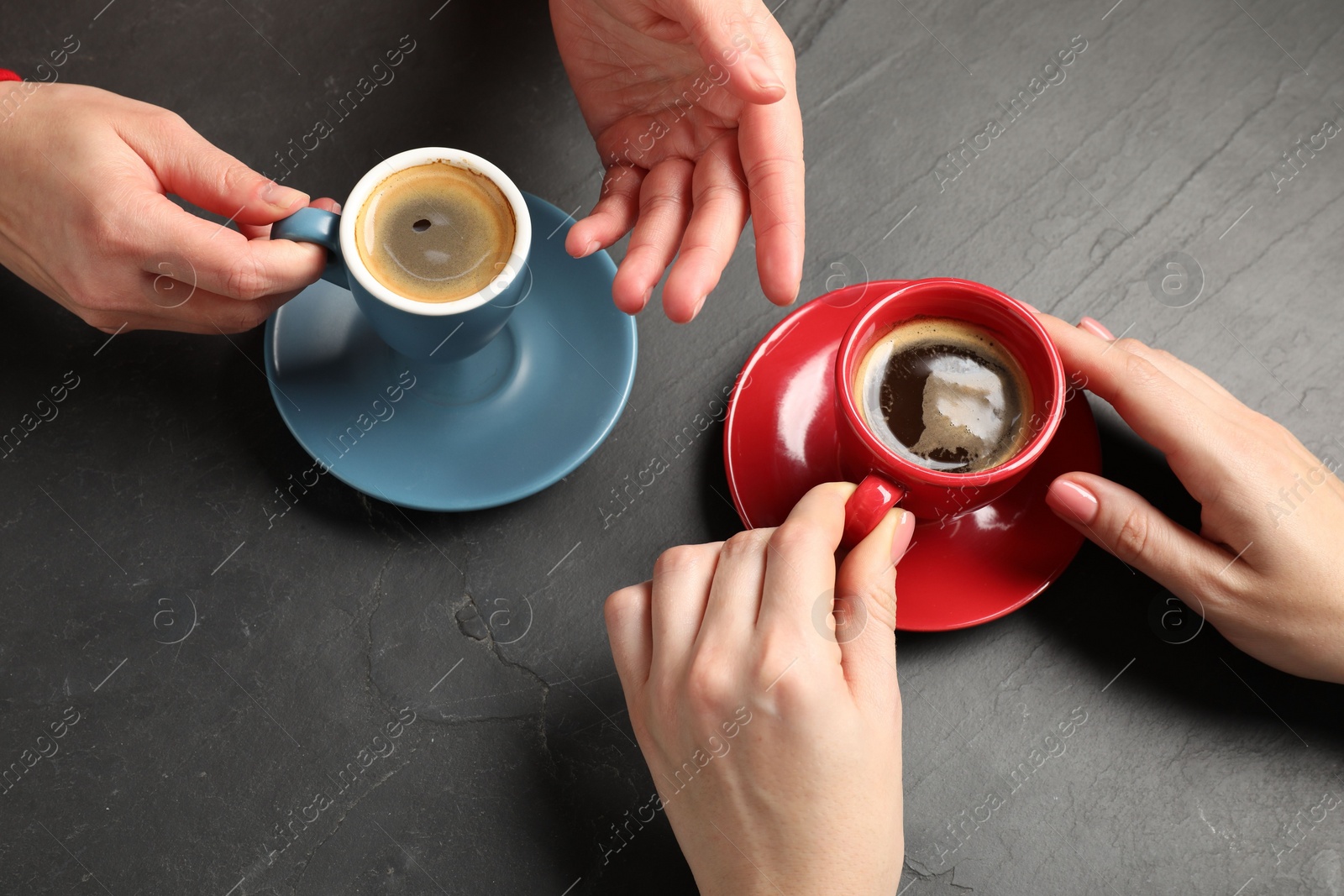 Photo of Women having coffee break at dark textured table, above view