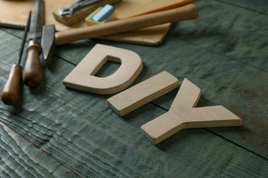 Photo of Abbreviation DIY made of letters and different tools on grey wooden table, closeup