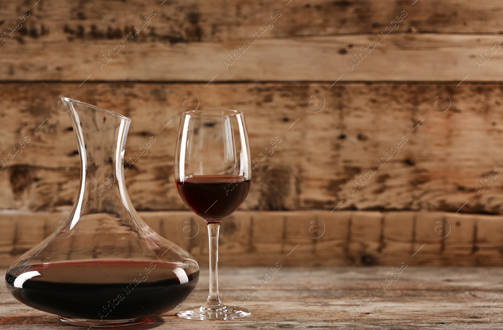 Photo of Elegant decanter and glass with red wine on wooden table