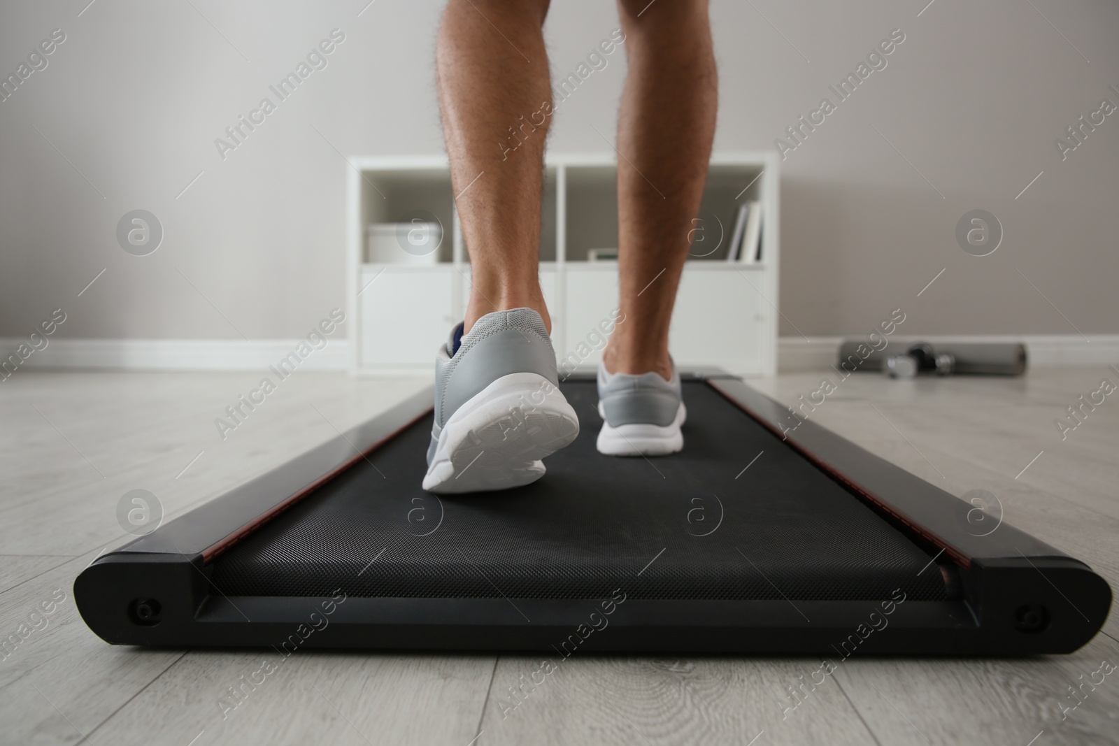 Photo of Sporty man training on walking treadmill at home, closeup