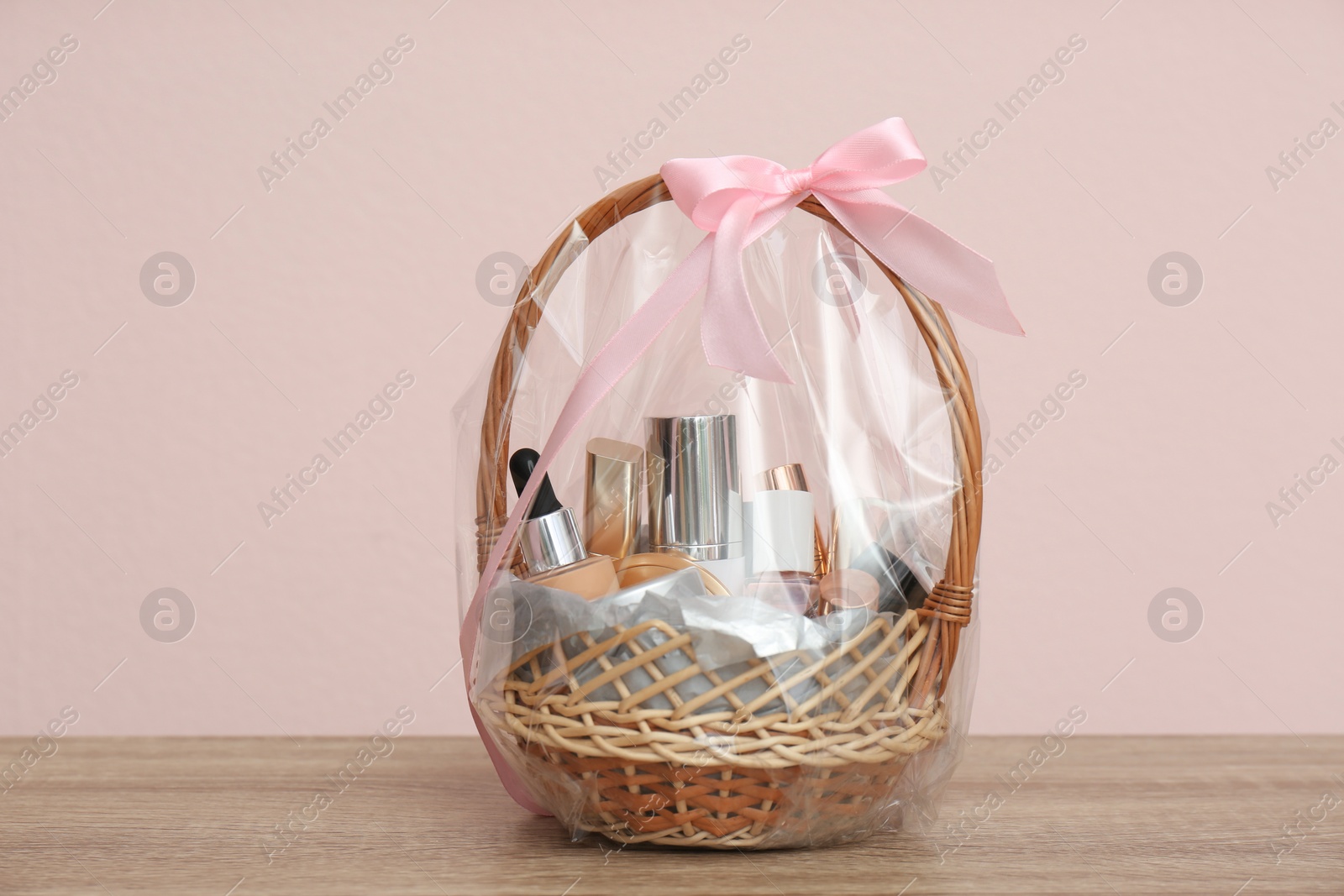 Photo of Wicker gift basket with cosmetic products on wooden table