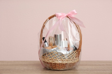 Photo of Wicker gift basket with cosmetic products on wooden table