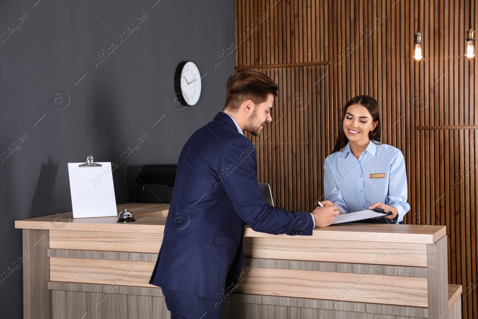 Photo of Receptionist registering client at desk in lobby