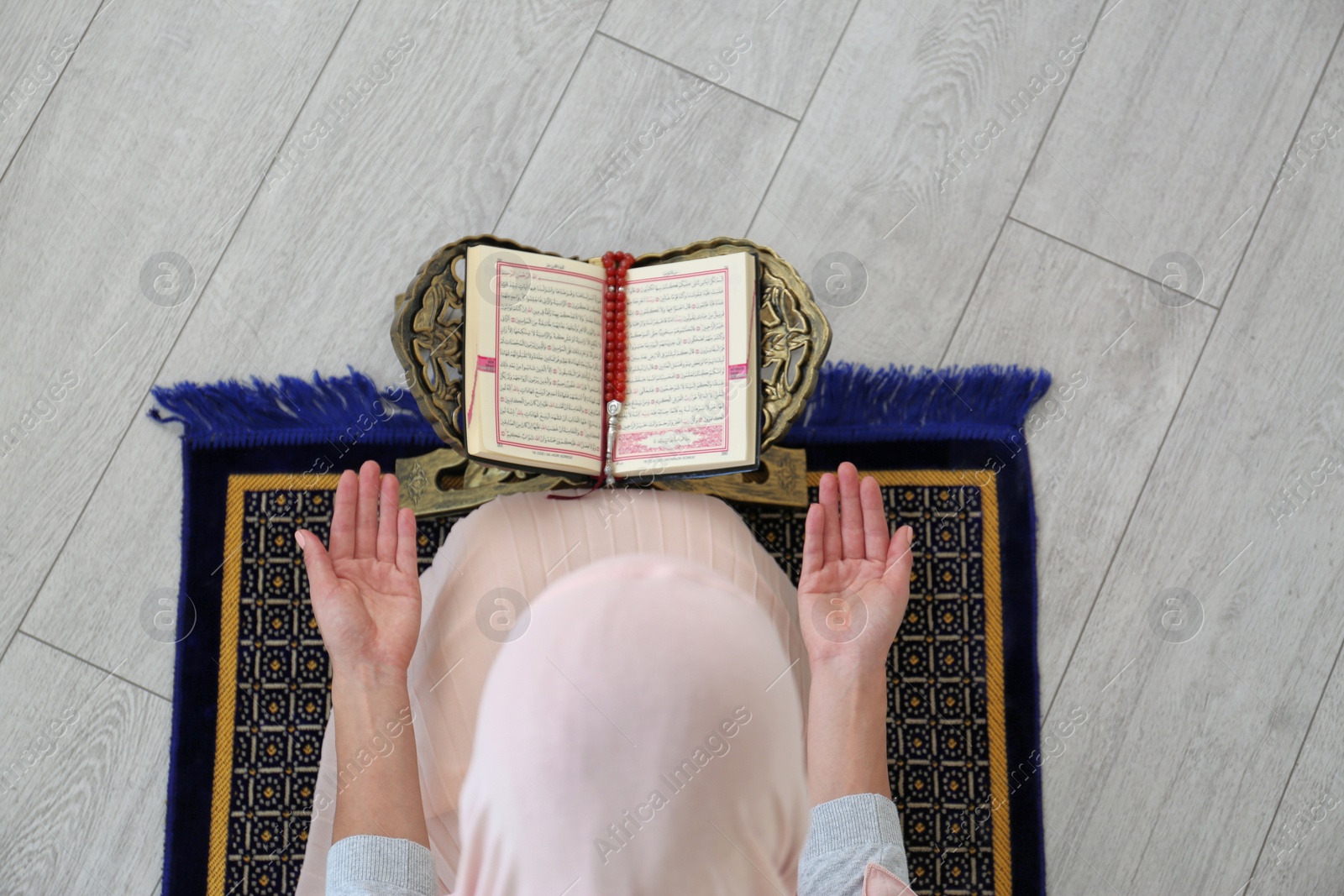 Photo of Muslim woman reading Koran indoors, top view