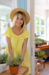 Photo of Young woman taking care of home plants at wooden table outdoors