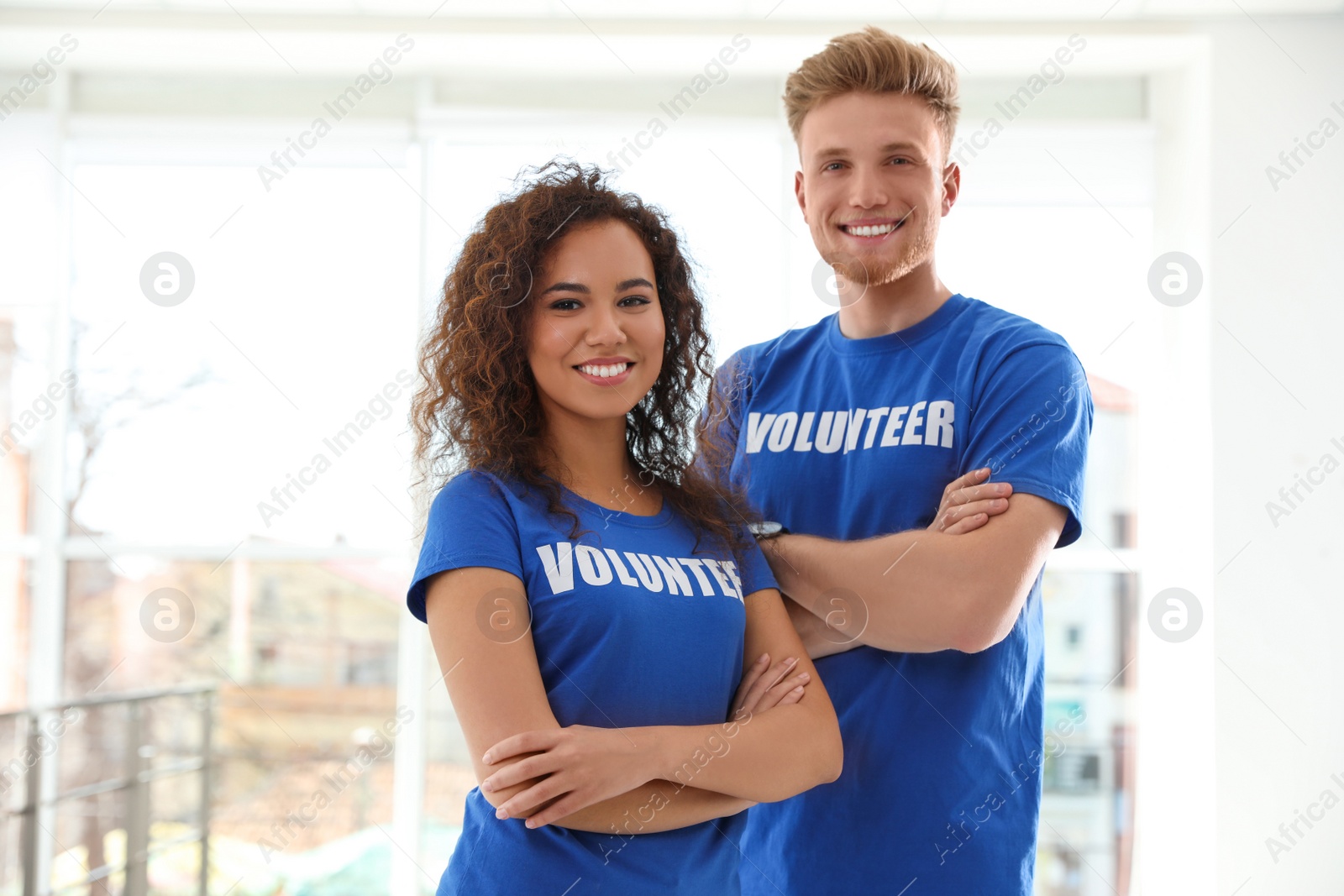 Photo of Portrait of happy volunteers in uniform indoors. Space for text