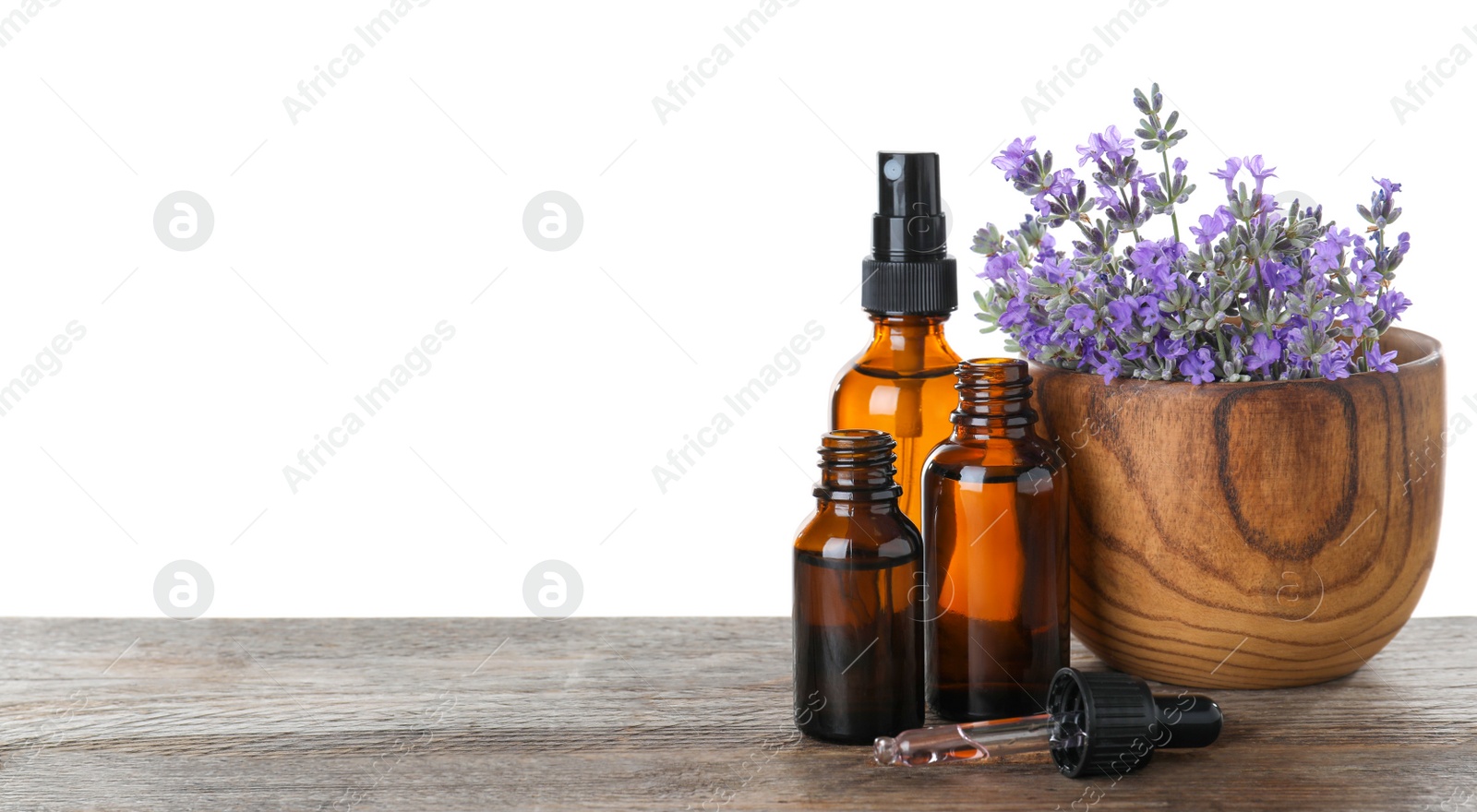 Photo of Bottles of essential oil and bowl with lavender flowers on wooden table against white background