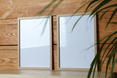 Empty frames on table near wooden wall. Mockup for design