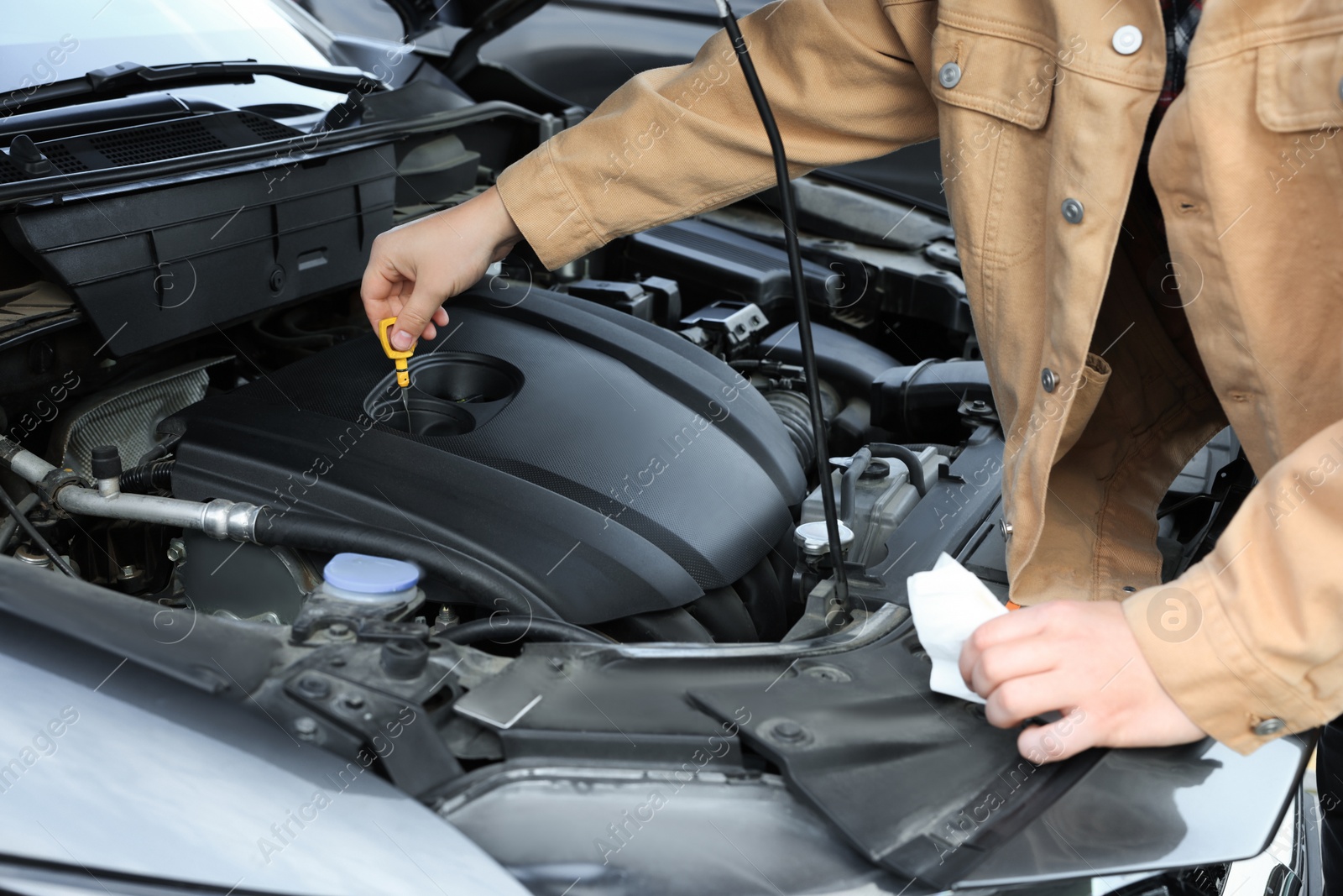 Photo of Man checking motor oil level in car with dipstick, closeup