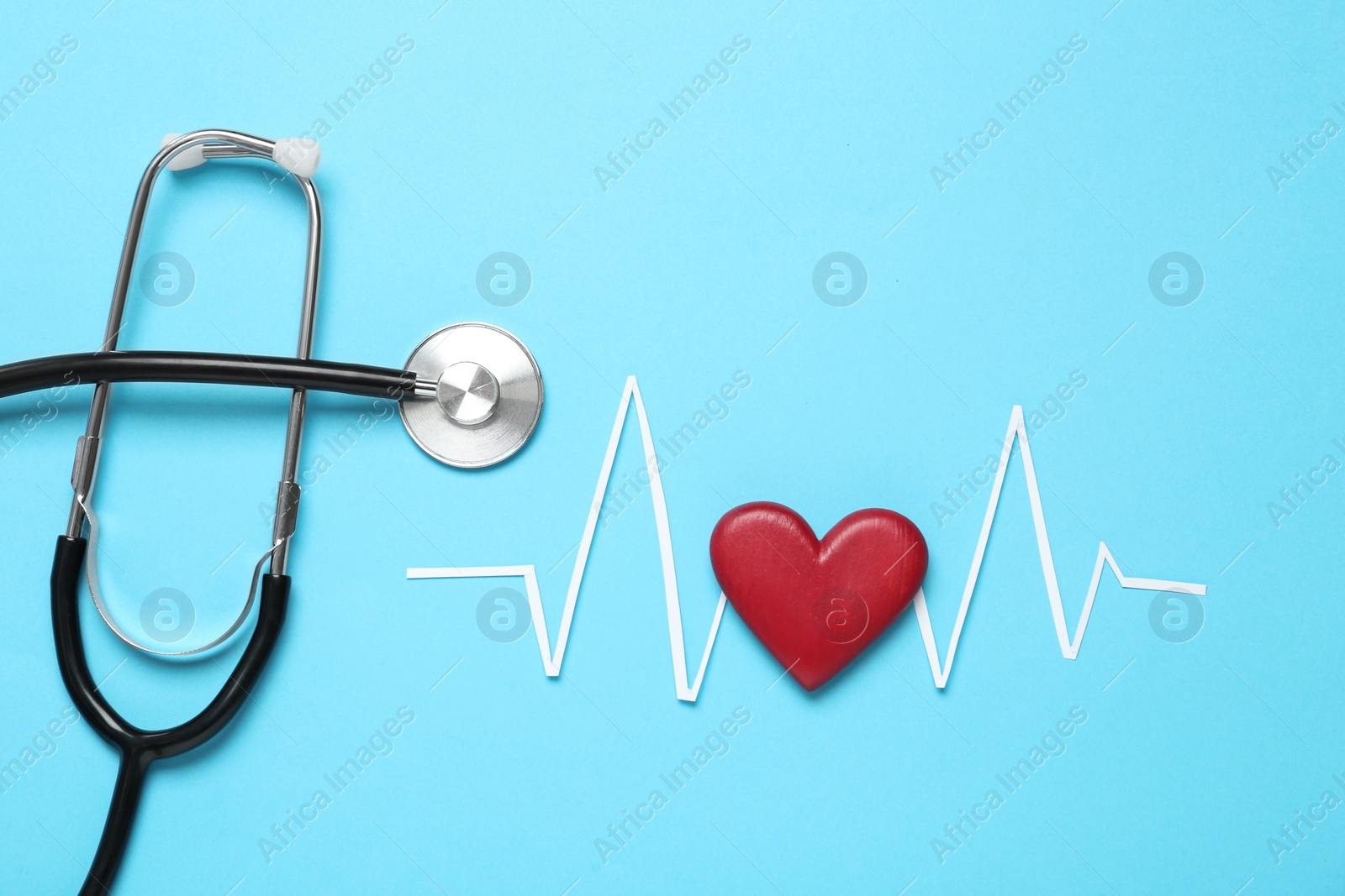 Photo of Paper cardiogram line, red heart and stethoscope on light blue background, flat lay