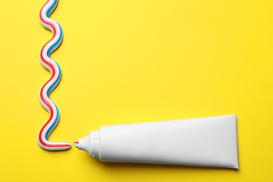 Photo of Blank tube with squeezed out toothpaste on yellow background, flat lay. Space for text