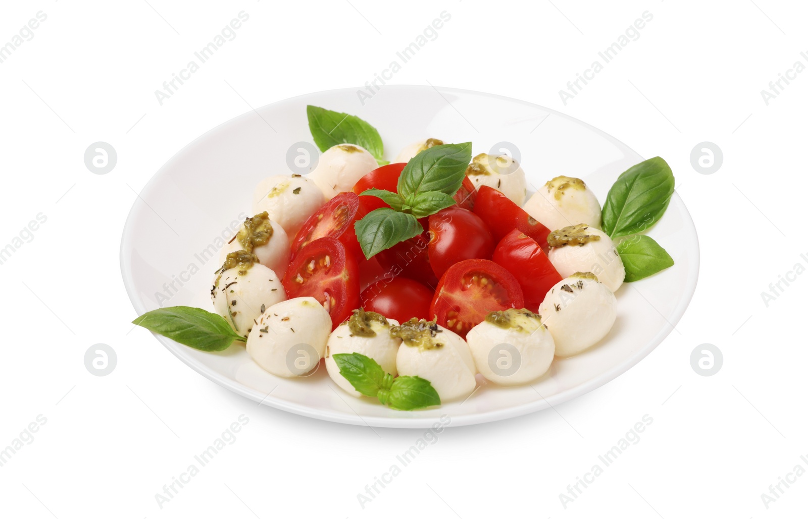 Photo of Plate of tasty Caprese salad with mozzarella, tomatoes, basil and pesto sauce isolated on white