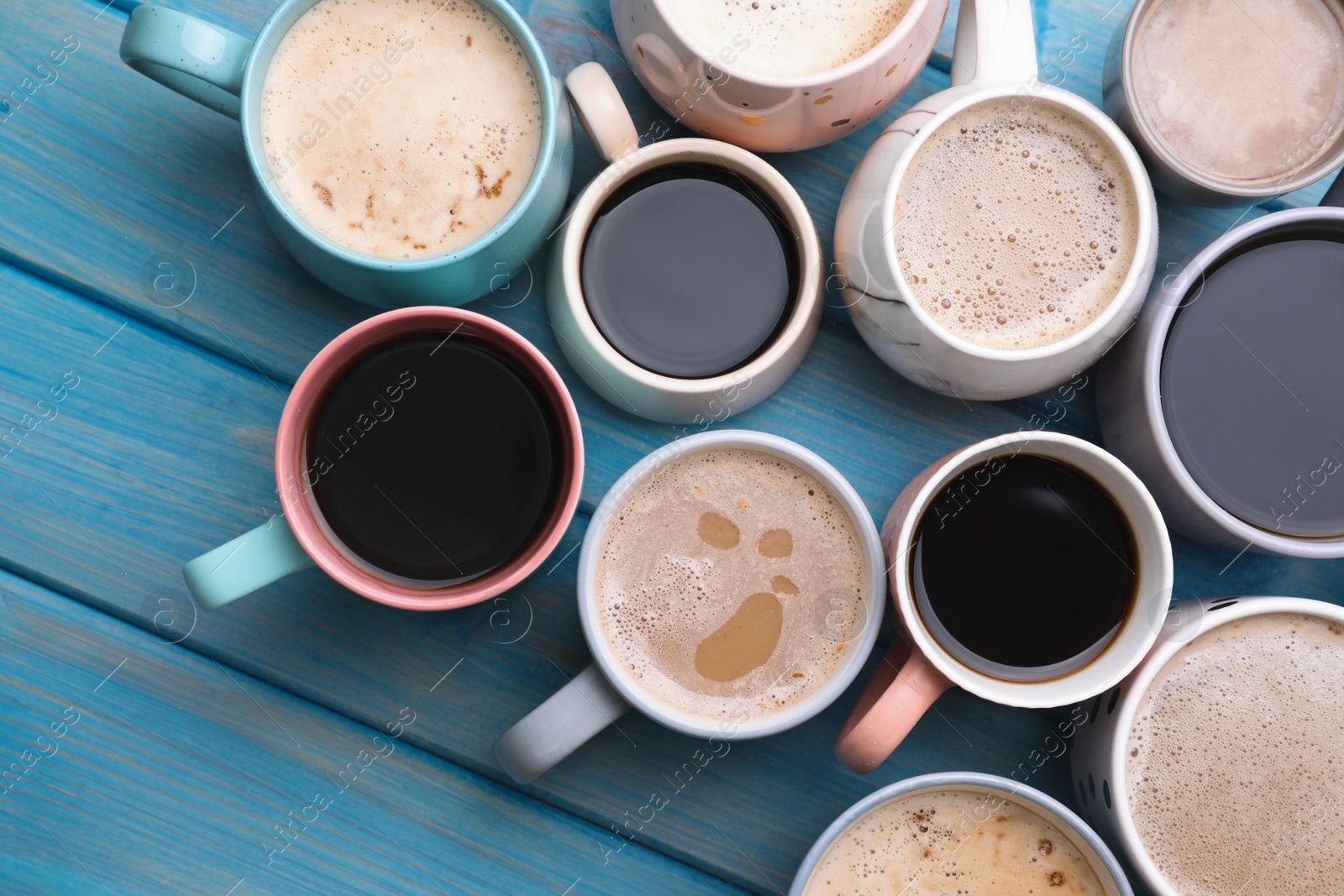 Photo of Many cups of different coffee drinks on light blue wooden table, flat lay