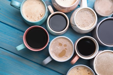 Photo of Many cups of different coffee drinks on light blue wooden table, flat lay