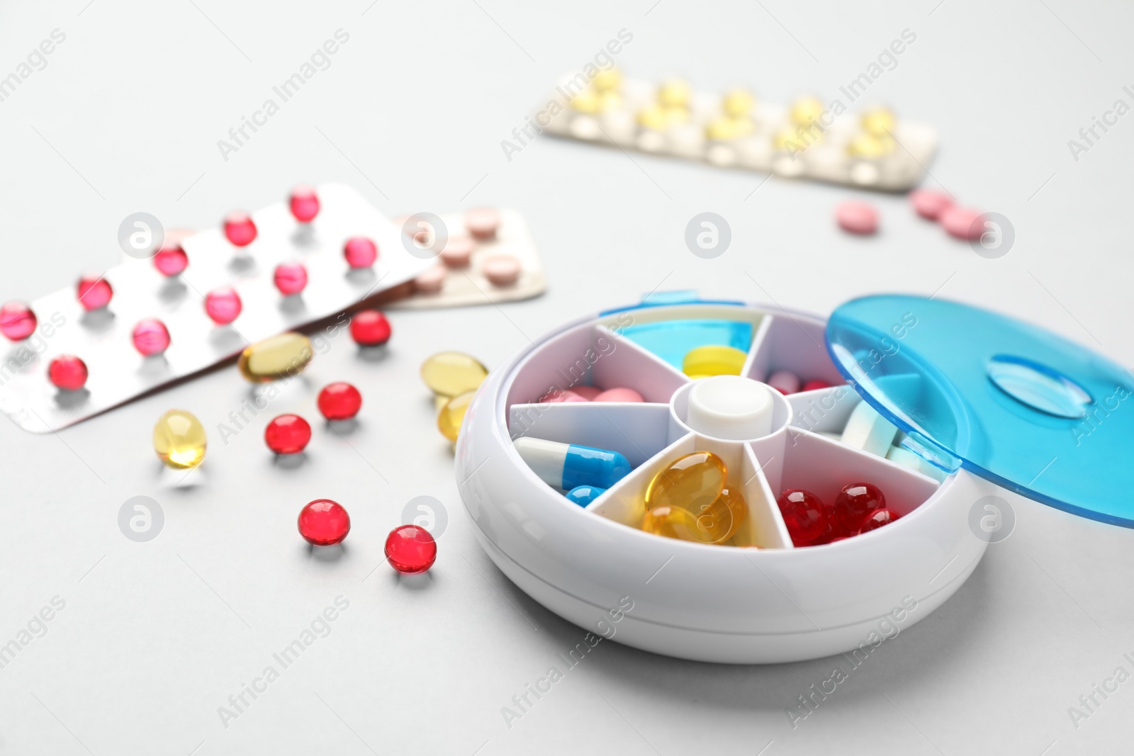Photo of Plastic box with different pills on light grey background