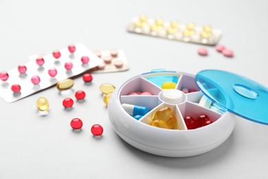 Plastic box with different pills on light grey background