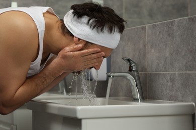 Photo of Man with headband washing his face in bathroom