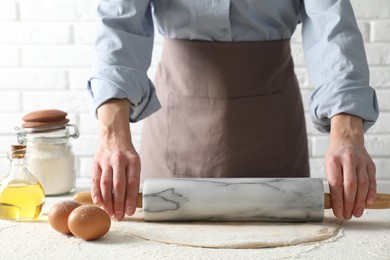 Photo of Woman rolling raw dough at table, closeup