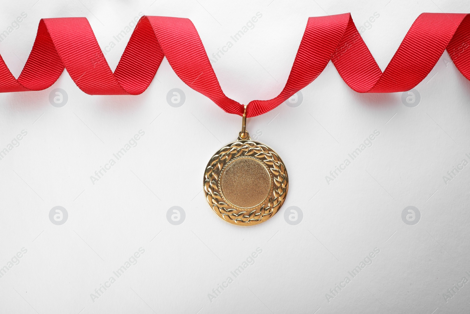 Photo of Gold medal on white background, top view with space for text. Symbol of victory