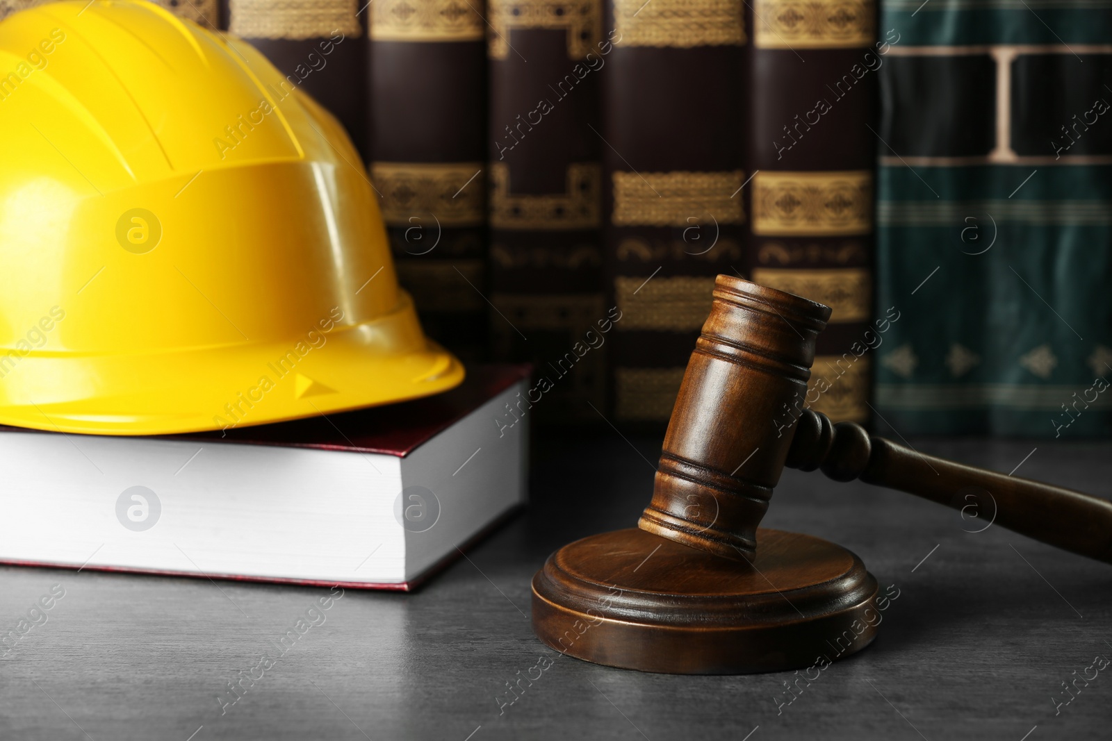 Photo of Labour, construction and land law concepts. Judge gavel, books with protective helmet on grey table