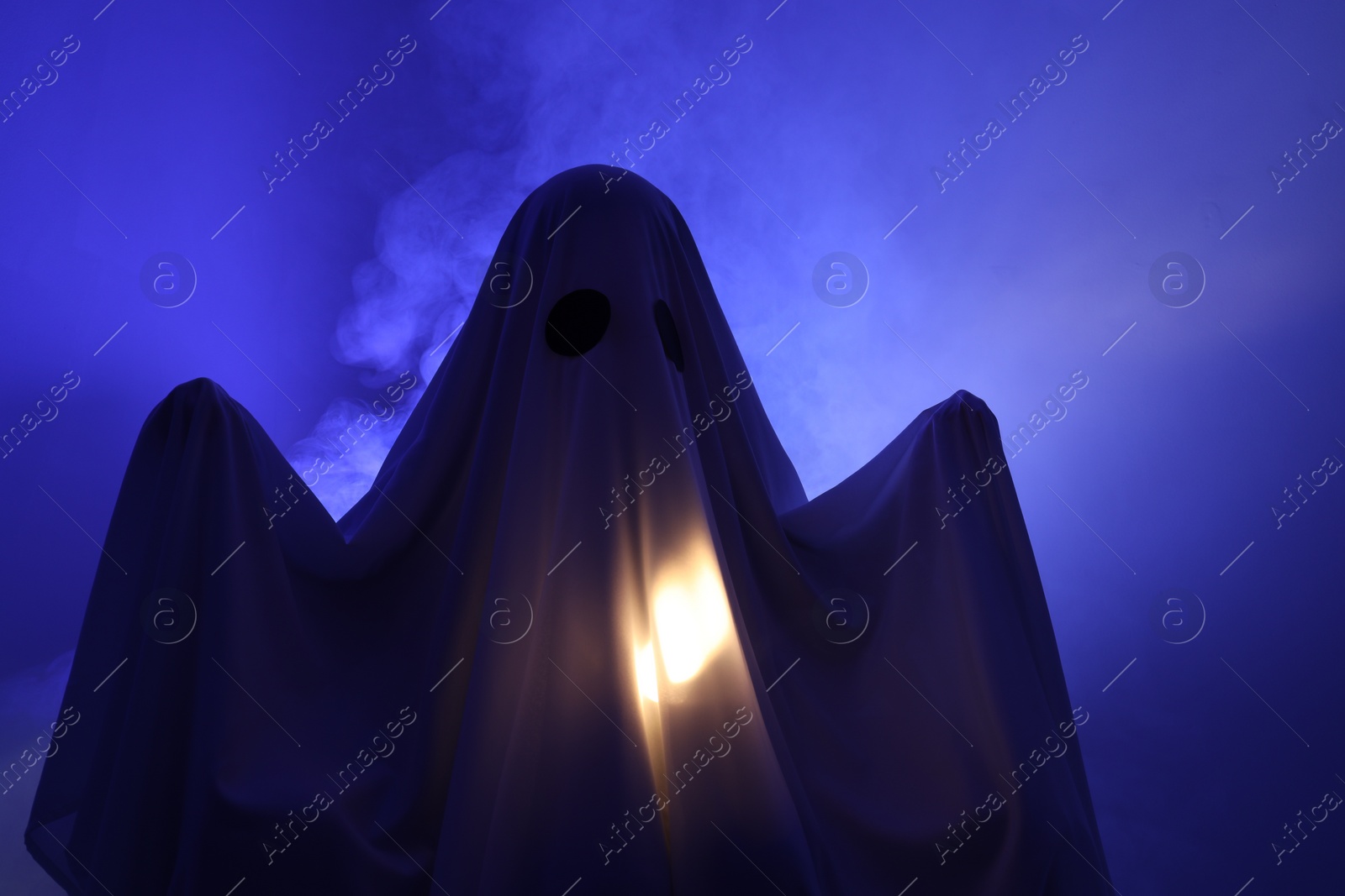 Photo of Creepy ghost. Woman covered with sheet in blue light