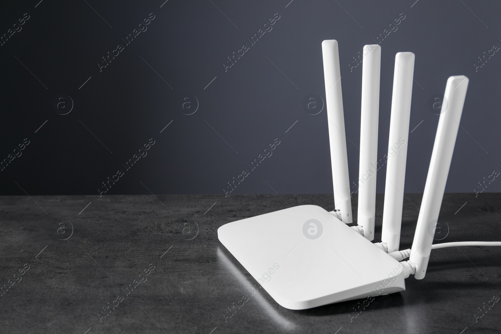 Photo of New stylish Wi-Fi router on black textured table. Space for text
