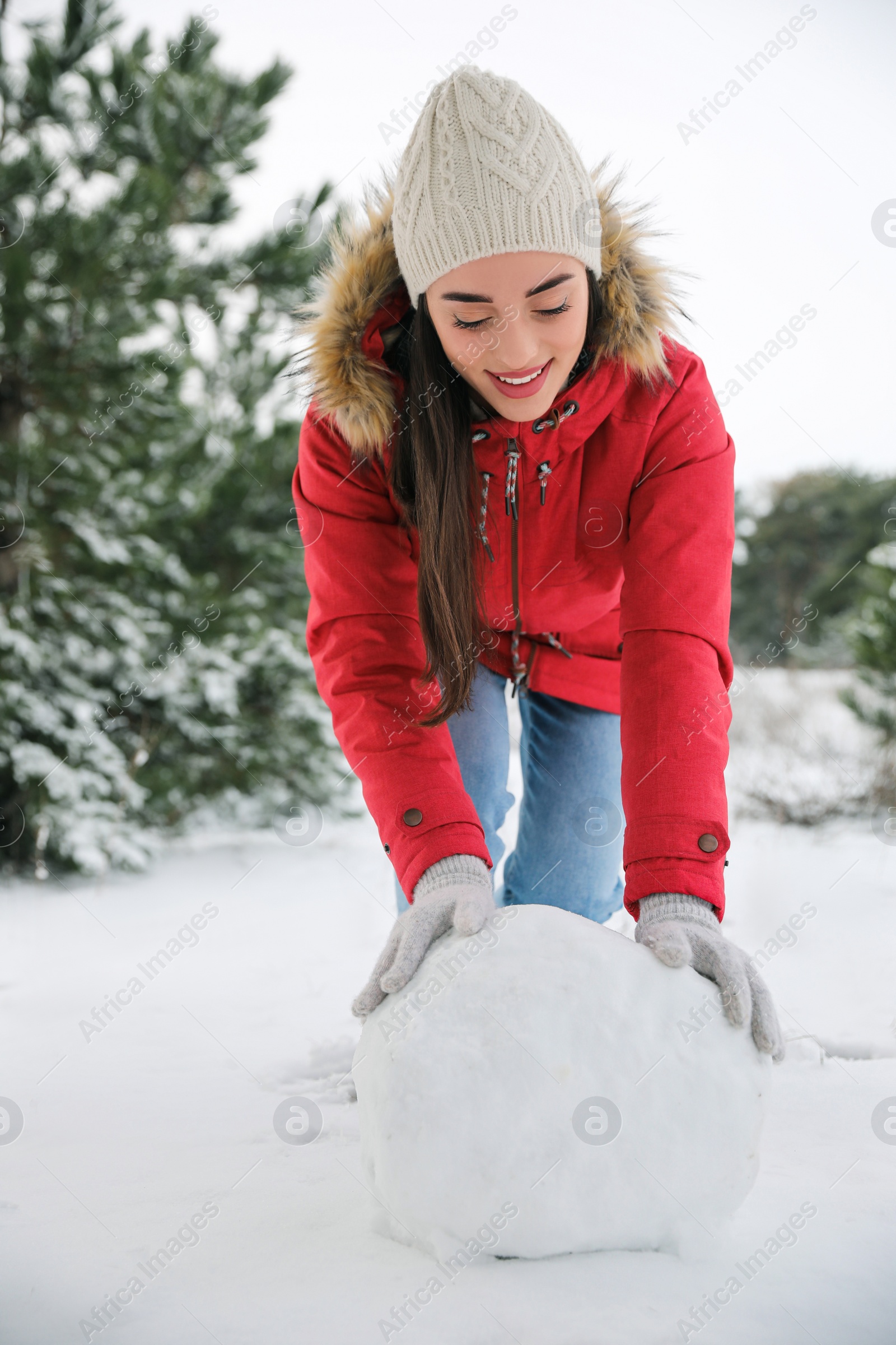 Photo of Young woman rolling snowball outdoors on winter day