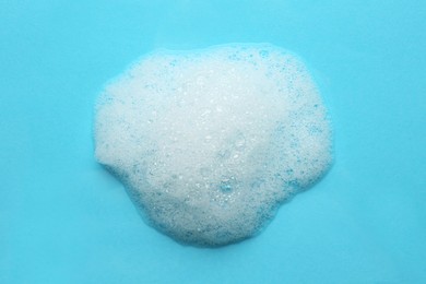 Photo of Drop of bath foam on turquoise background, top view